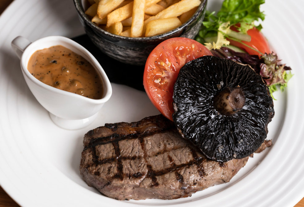 Steak with mushroom, tomato, salad, chips and peppercorn sauce.