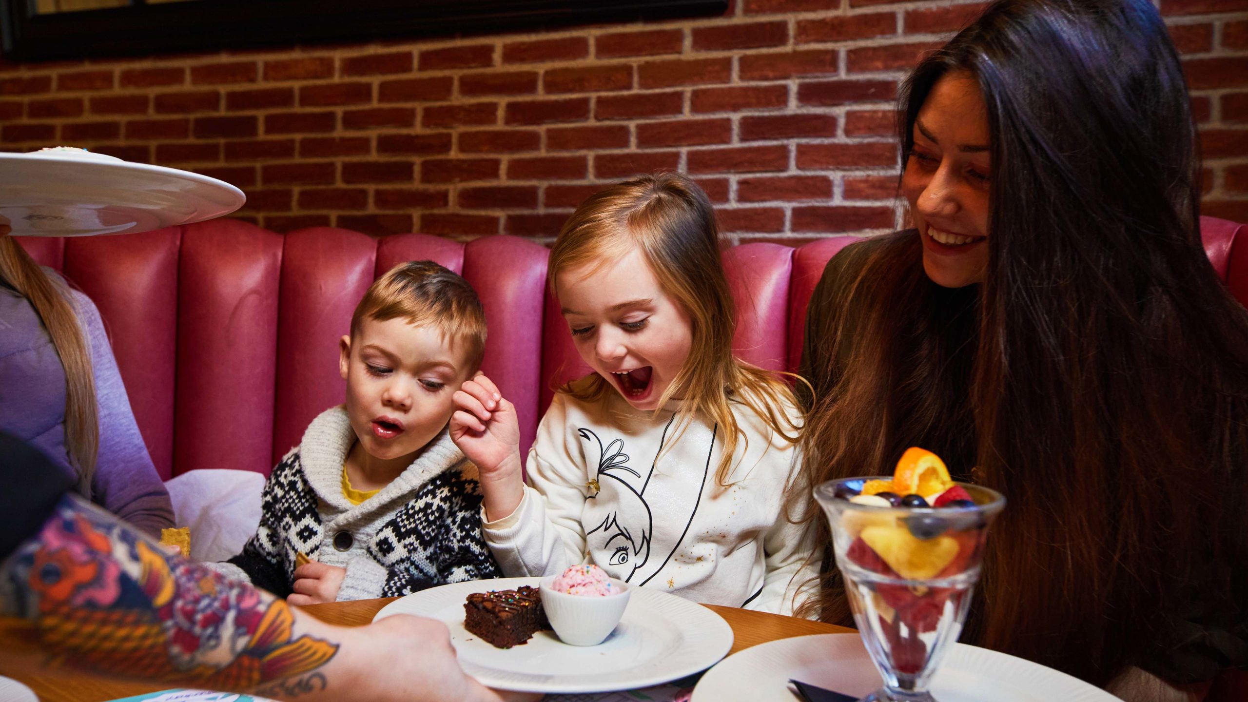 Woman with two kids are enjoying desserts in our restaurant.