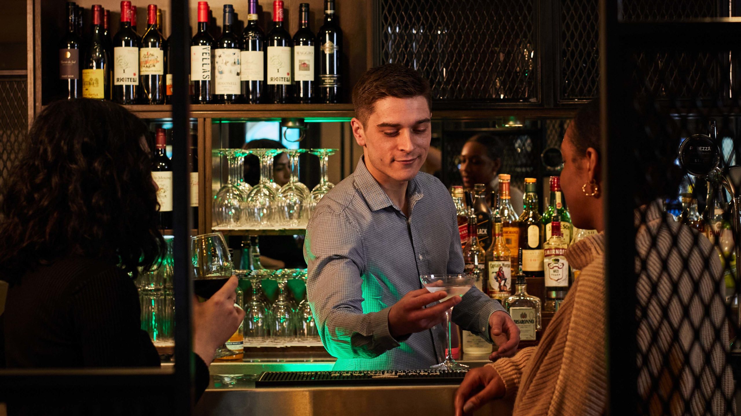 Bartender is serving drink to a woman.